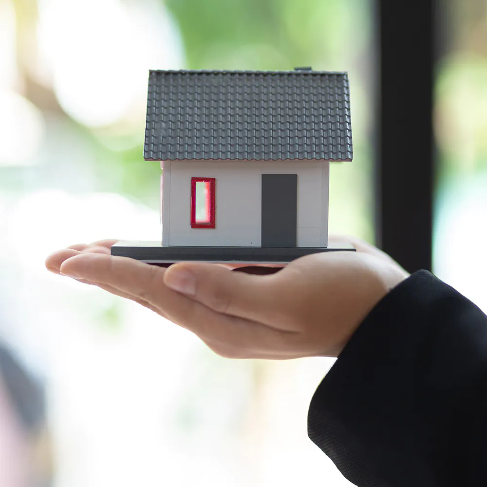 Modellino architettonico di abitazione sostenuto da una mano per servizio di valutazione immobiliare professionale a Jesolo.